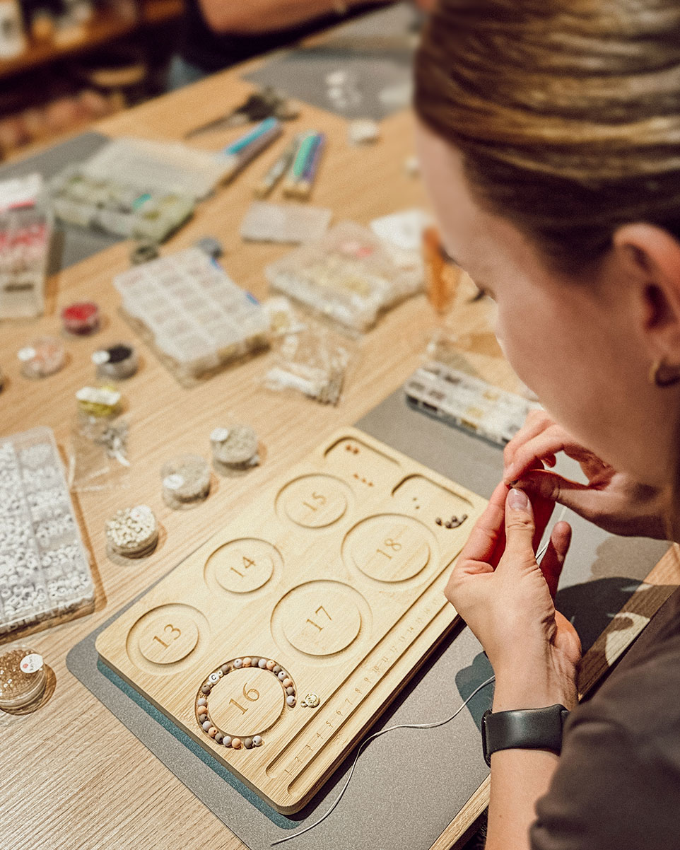 Frau fädelt Perlen für ein Armband beim Kreativ-Workshop in Düsseldorf
