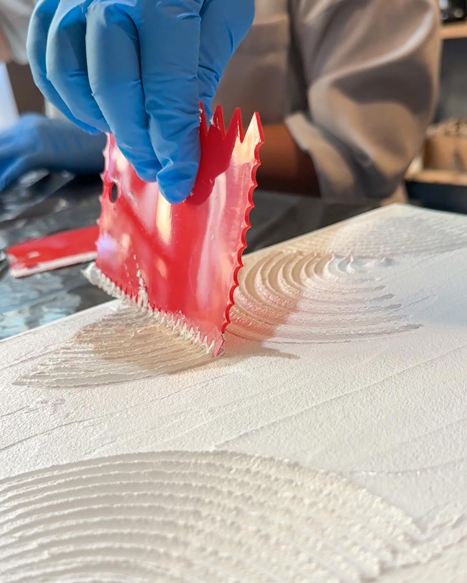 Hand mit Spachtel trägt Strukturpaste im Kreativ-Workshop in Düsseldorf auf