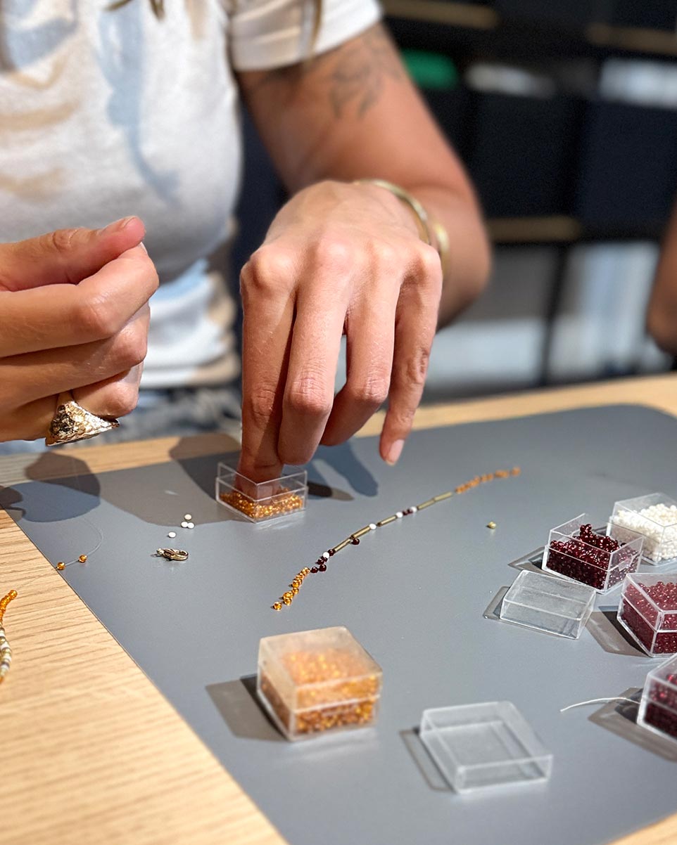 Teilnehmerin fädelt Perlen für ein Armband im Kreativ-Workshop in Düsseldorf