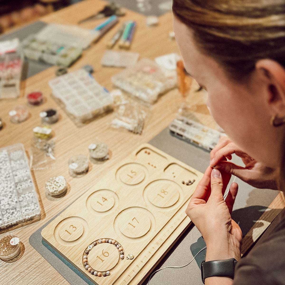 Teilnehmerin beim Perlen-Workshop in Düsseldorf fädelt ein Armband aus weißen und grünen Perlen