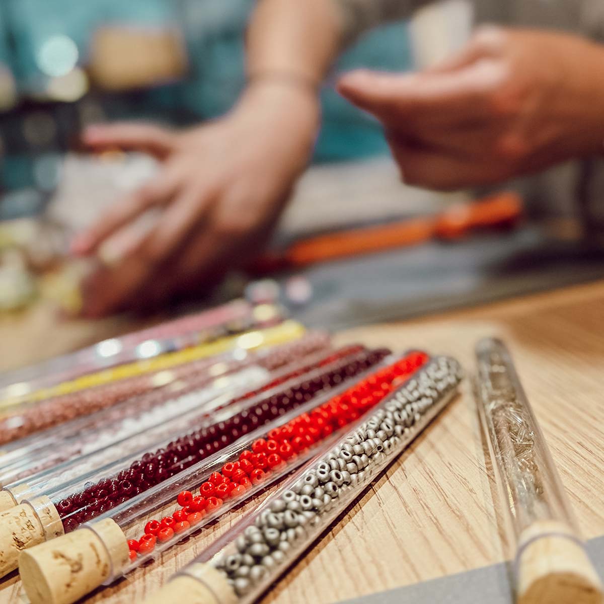 Glasröhrchen mit roten, silbernen und bunten Perlen auf dem Tisch eines Perlen-Workshops in Düsseldorf