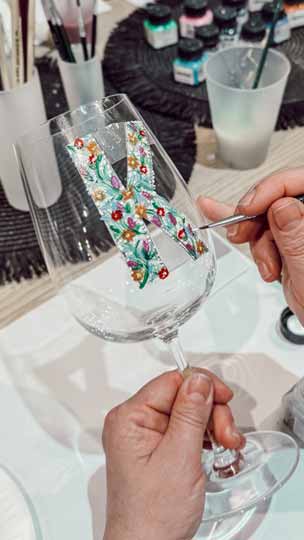 Teilnehmer bemalt ein personalisiertes Weinglas im Kreativworkshop.