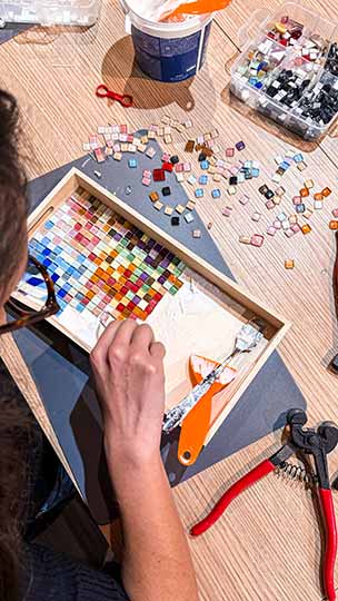 Teilnehmerin gestaltet ein buntes Mosaik-Tablett im DIY Workshop bei zehn null zwo in Düsseldorf