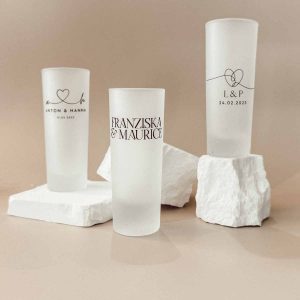 Verschiedene personalisierte Schnapsgläser mit Namen und Datum für Hochzeiten.